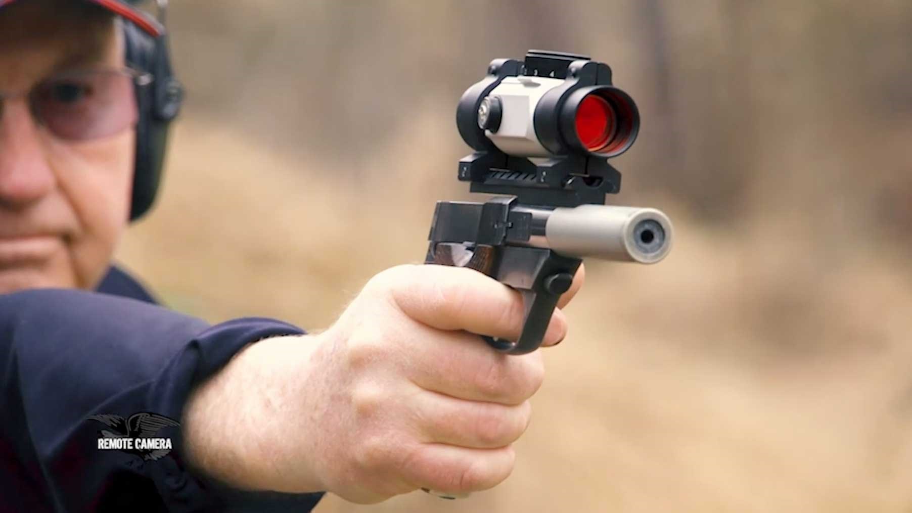 NRA Firearms Instructor Larry Quandahl aims a red-dot-equipped .22-caliber pistol downrange.