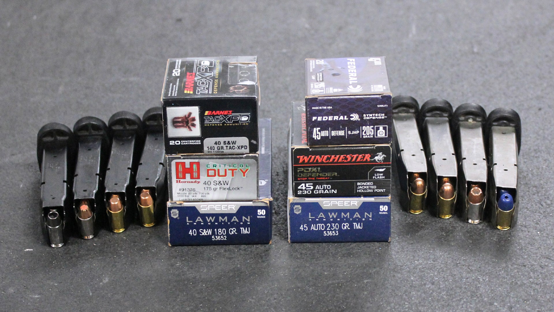 Pistol magazines loaded with ammunition shown next to six ammunition boxes of various types and colors