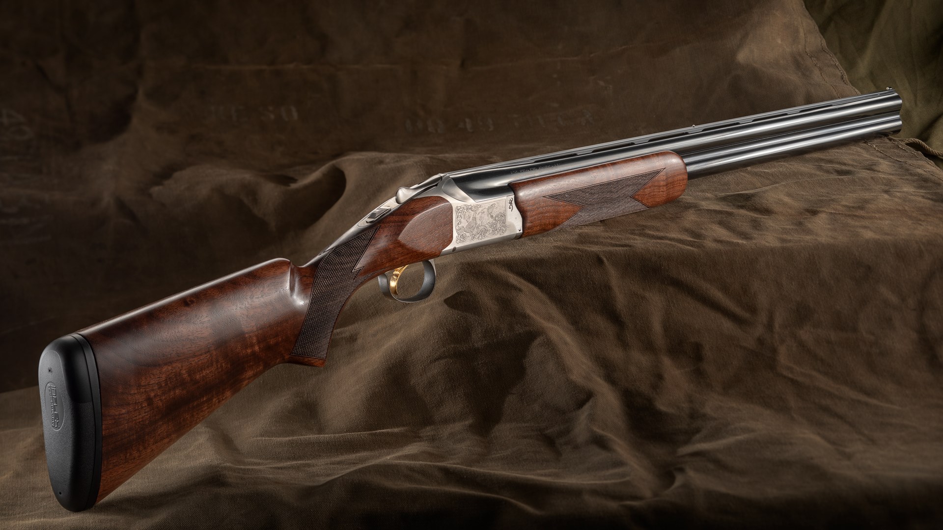 Browning Arms Citori 825 Field over-under shotgun right-side dynamic view walnut stock silver boxlock engraved receiver blued barrels shown on military canvas