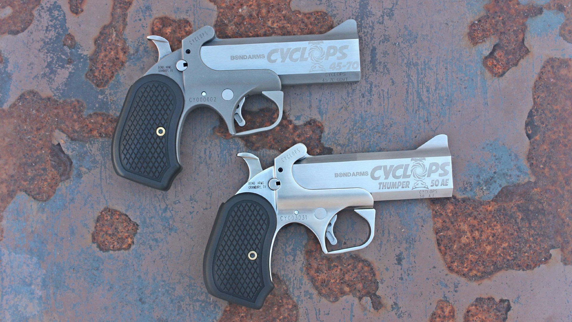 Two Bond Arms Cyclops pistols resting on a rusted surface.