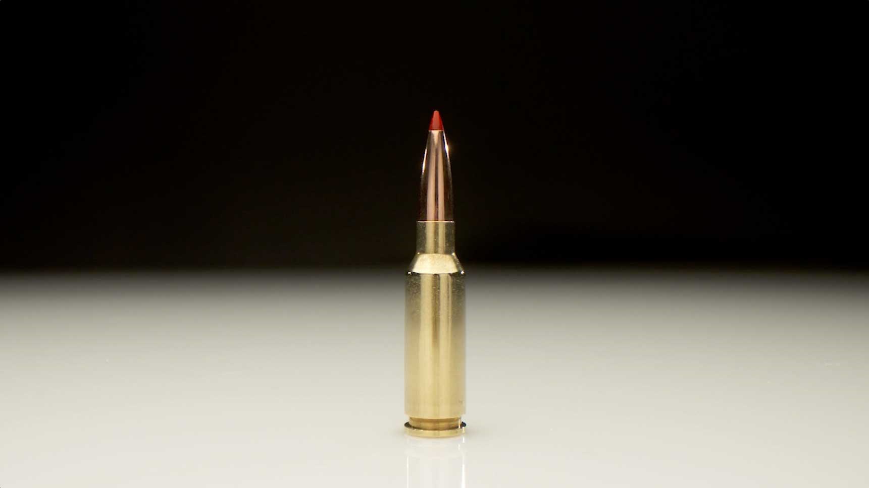 Hornady 6mm ARC cartridge shown on a white table with a black background.