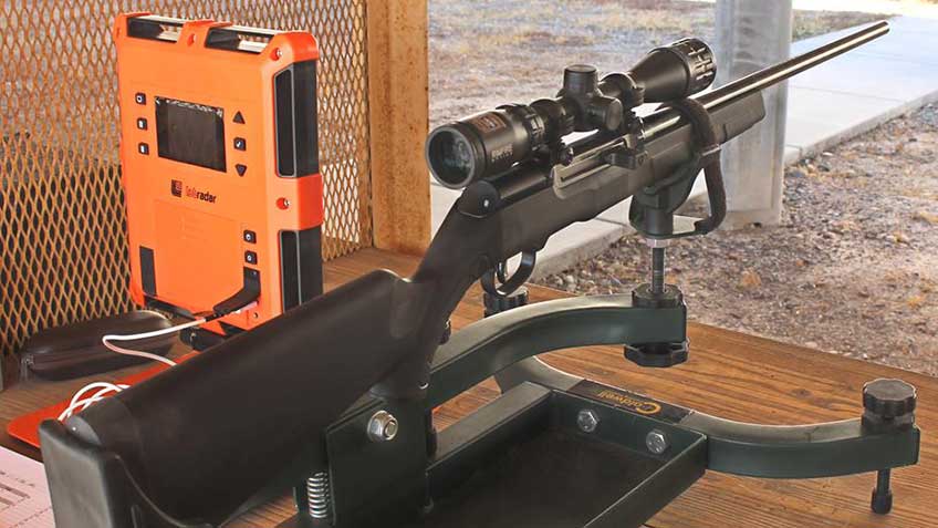 Savage Arms A17 XP semi-automatic rifle shown on shooting bench in a mechanical rest with orange chronography equipment placed to the left of the rifle.