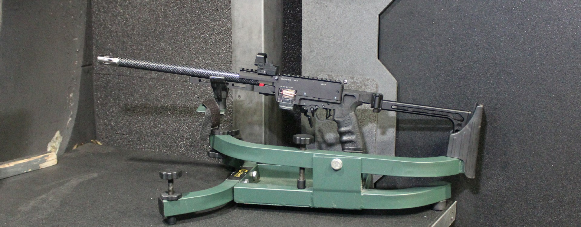 Custom rifle in cradle at indoor shooting range.