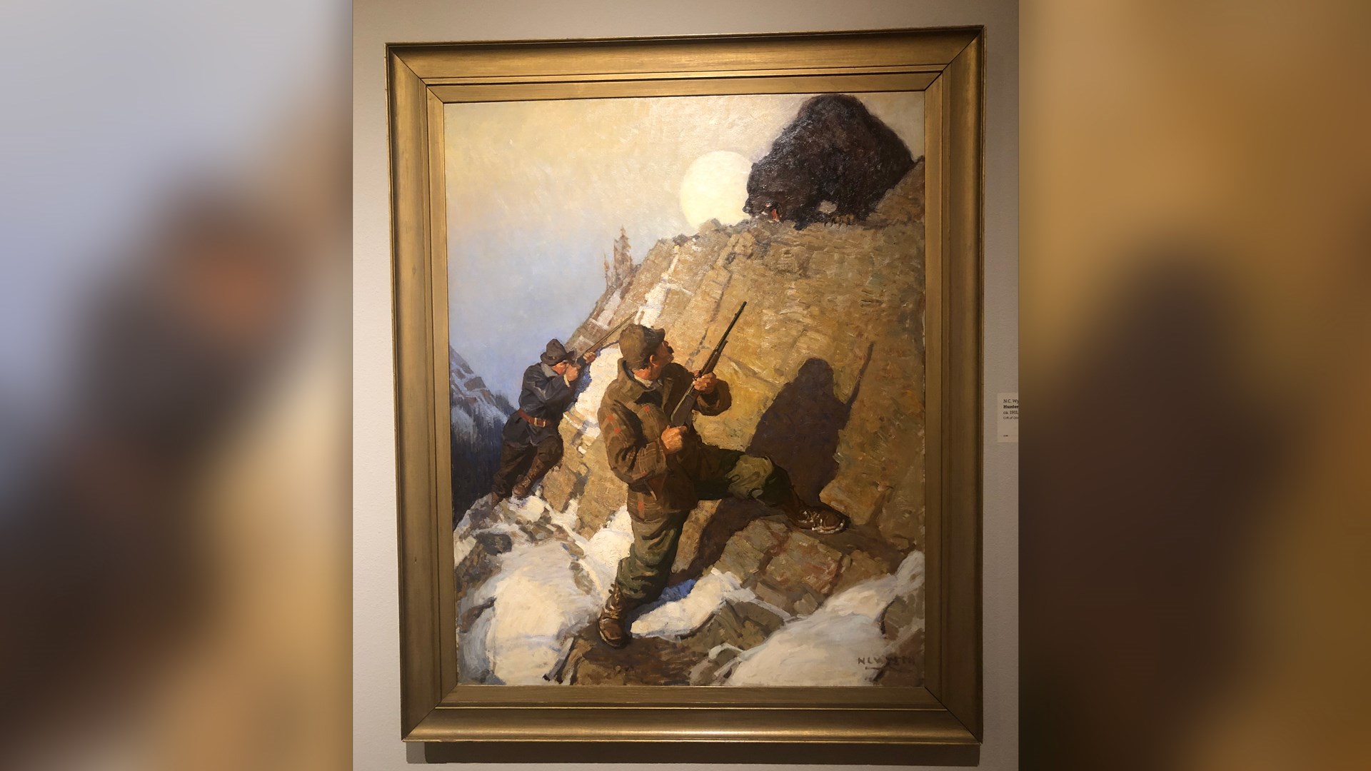 painting on wall in cody firearms museum of hunters facing grizzly bear on mountain rocks snow