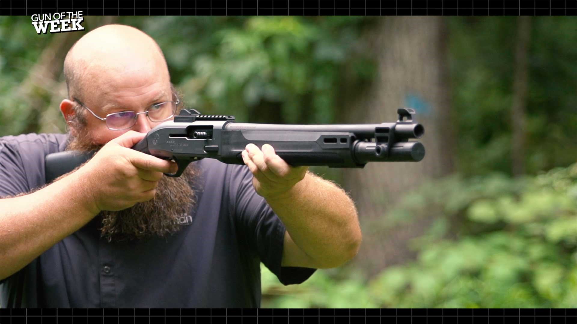A man aiming the Beretta A300 Ultima Patrol shotgun in the woods.