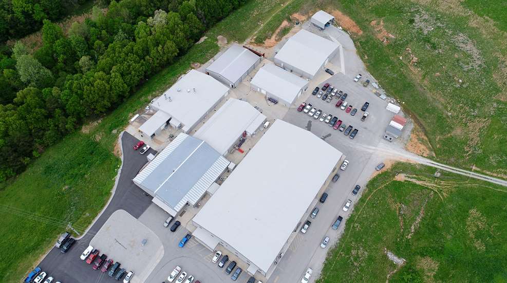 aerial photograph building manufacturing facility outdoors grass trees cars