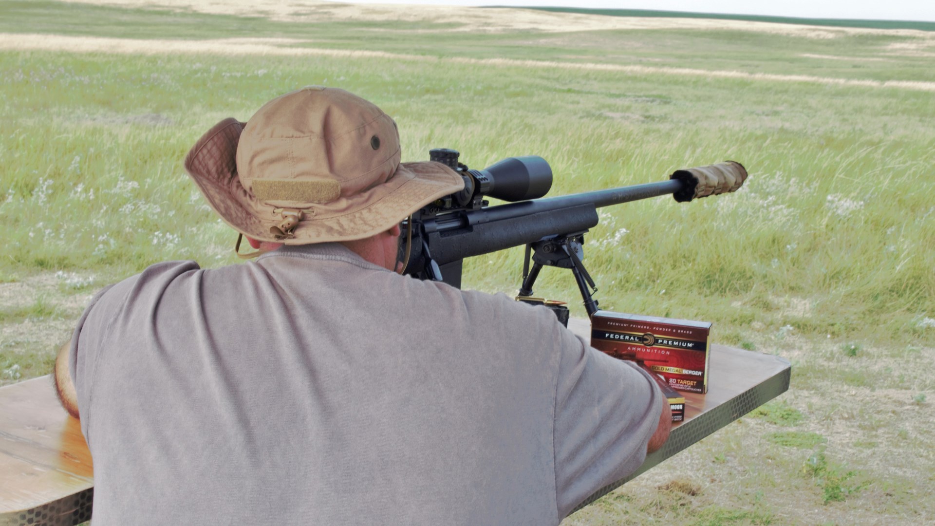 Rear view of man on bench with bolt-action rifle ammunition federal premium berger gold medal match bullets outdoors field hunting prairie dogs