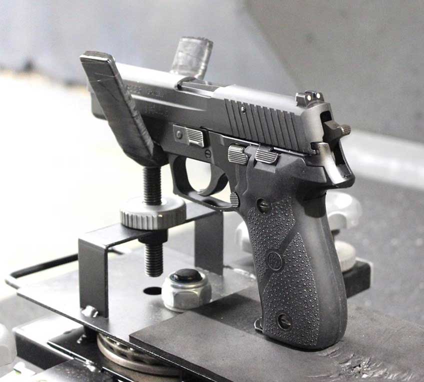 SIG Sauer P226 in gun cradle shooting range bench table lane black handgun