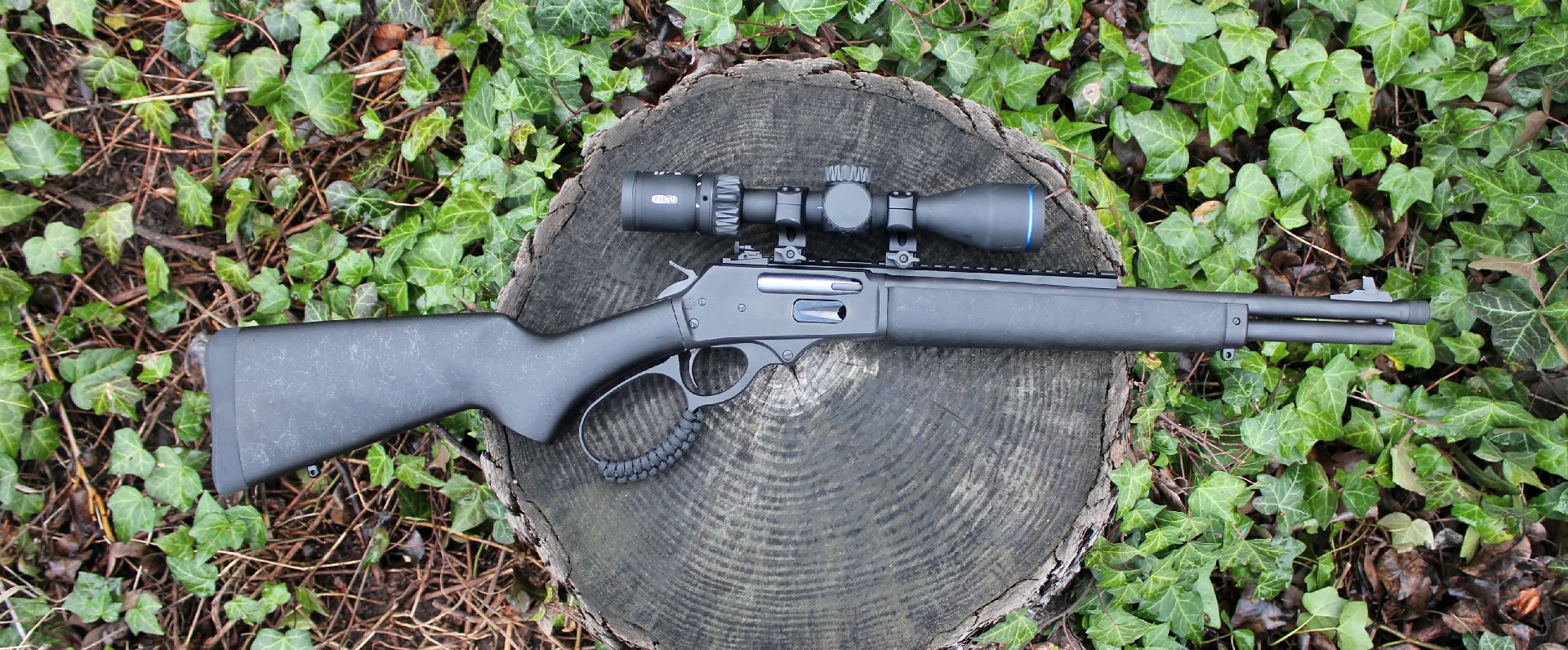 Rossi R95 Triple Black lever-action rifle right-side view shown with riflescope on stump log green ivy background black gun