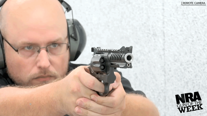 Man wearing protective shooting gear shooting a black and silver revolver.