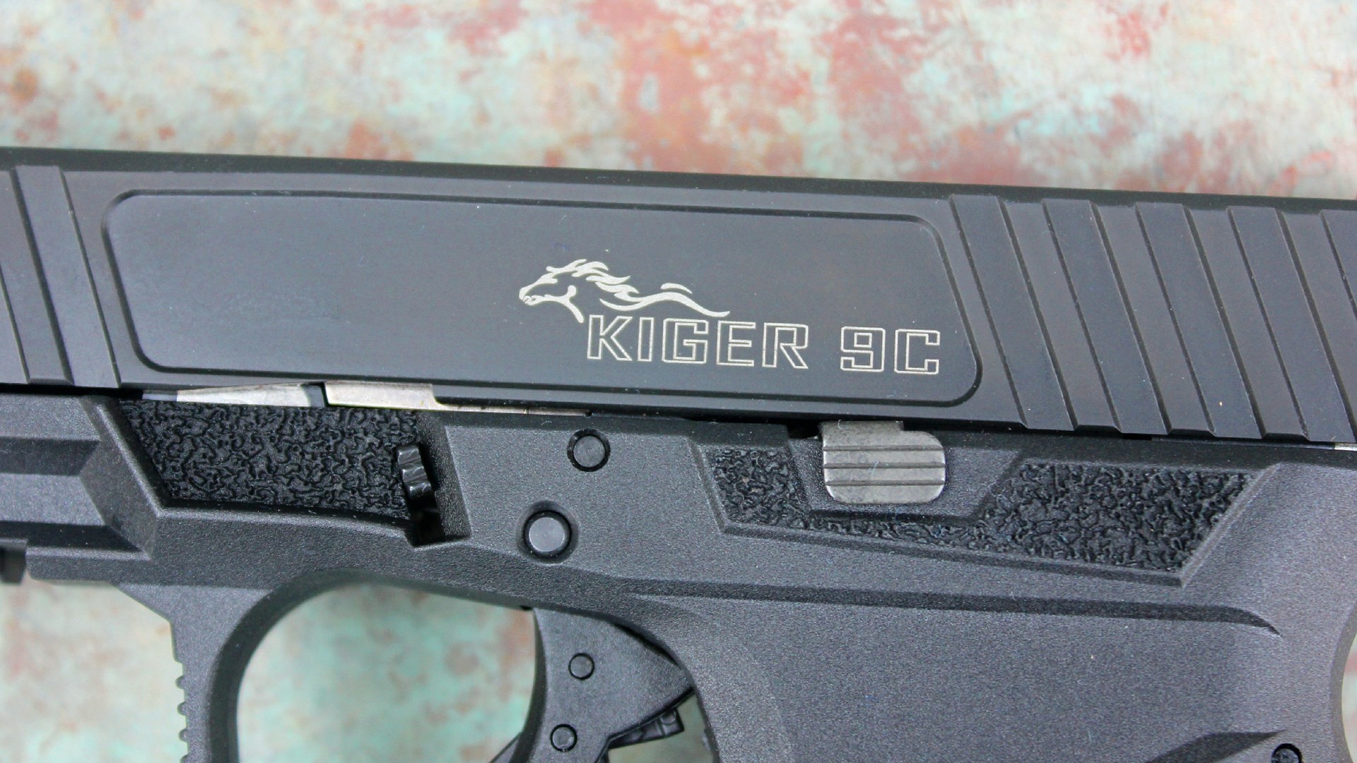 Close-up view of Anderson Manufacturing Kiger 9c pistol 9 mm semi-automatic glock gen 3 handgun black metal horse engraving