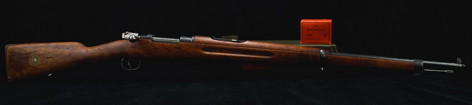 Right-side view of bolt-action m1896 swedish mauser rifle with ammunition box black background wood stock gun military surplus