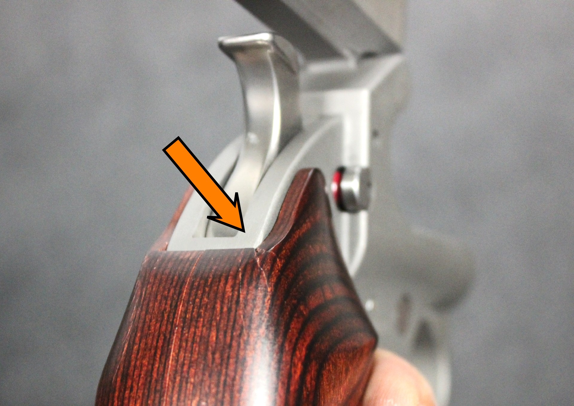 arrow pointing to crack in grip wood split closeup detail