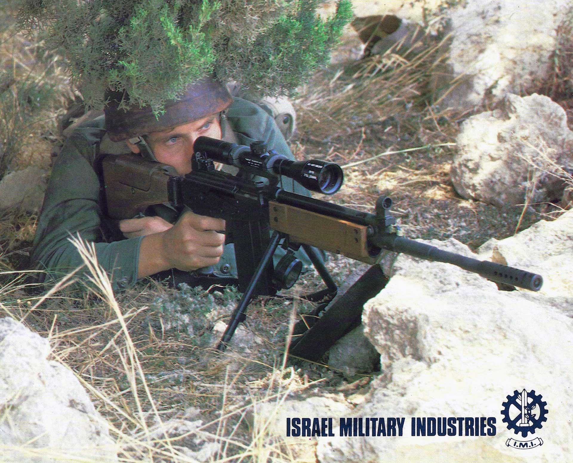 A man aims a Galil sniper rifle while hiding underneath brush.