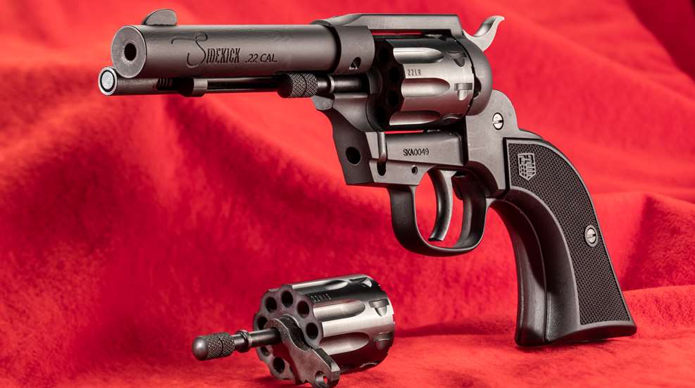 Diamondback Sidekick black metal gun revolver left-side dynamic view red background spare cylinder
