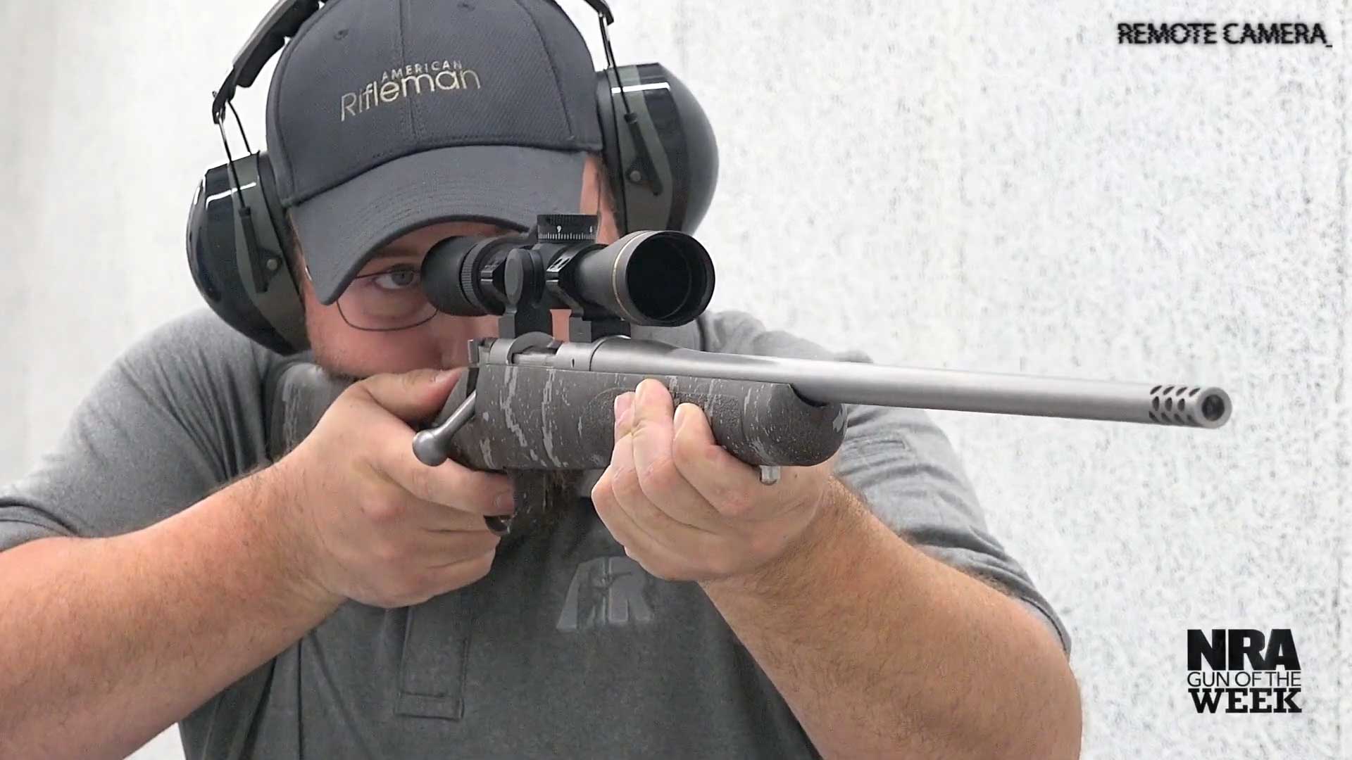 man shooting kimber america 84m pro desolve blak bolt-action rifle remote camera on shooting range white background