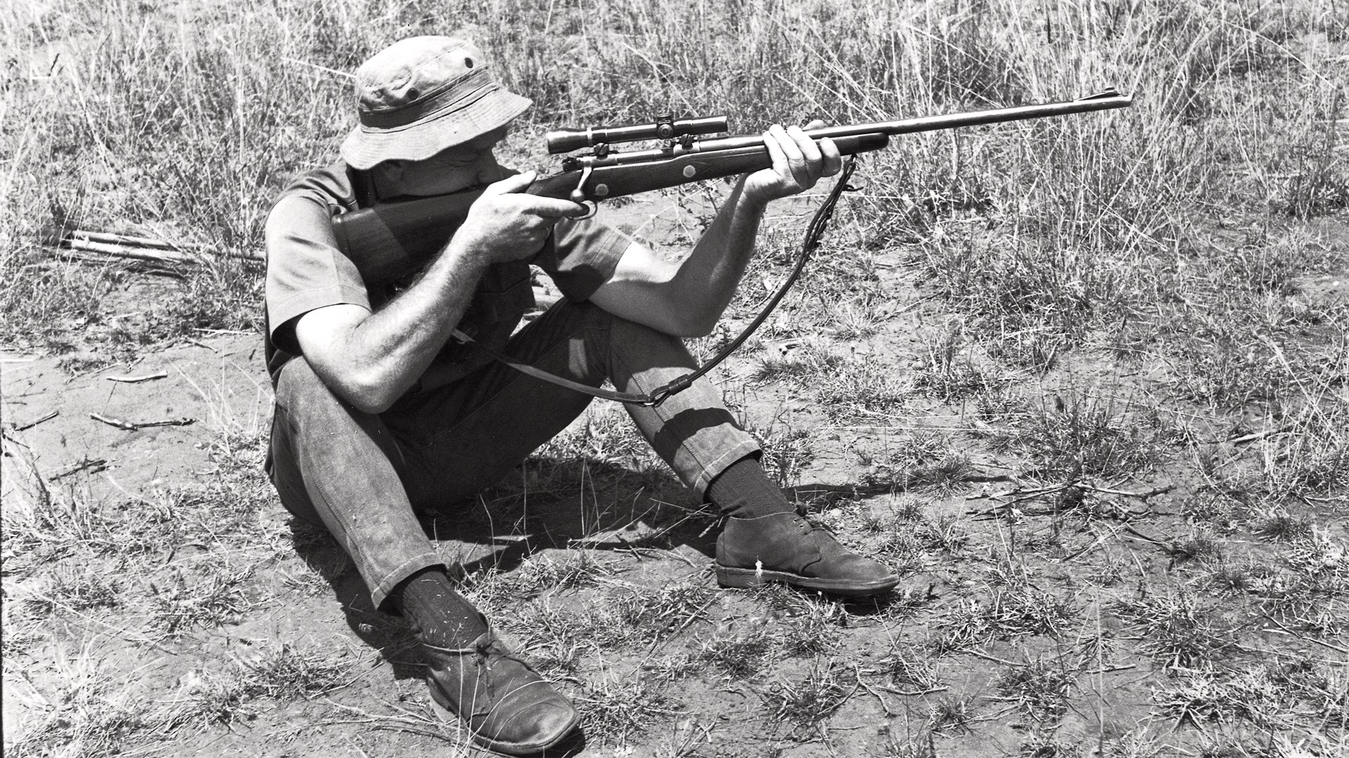 Finn Aagard sitting in the field with a bolt-action hunting rifle
