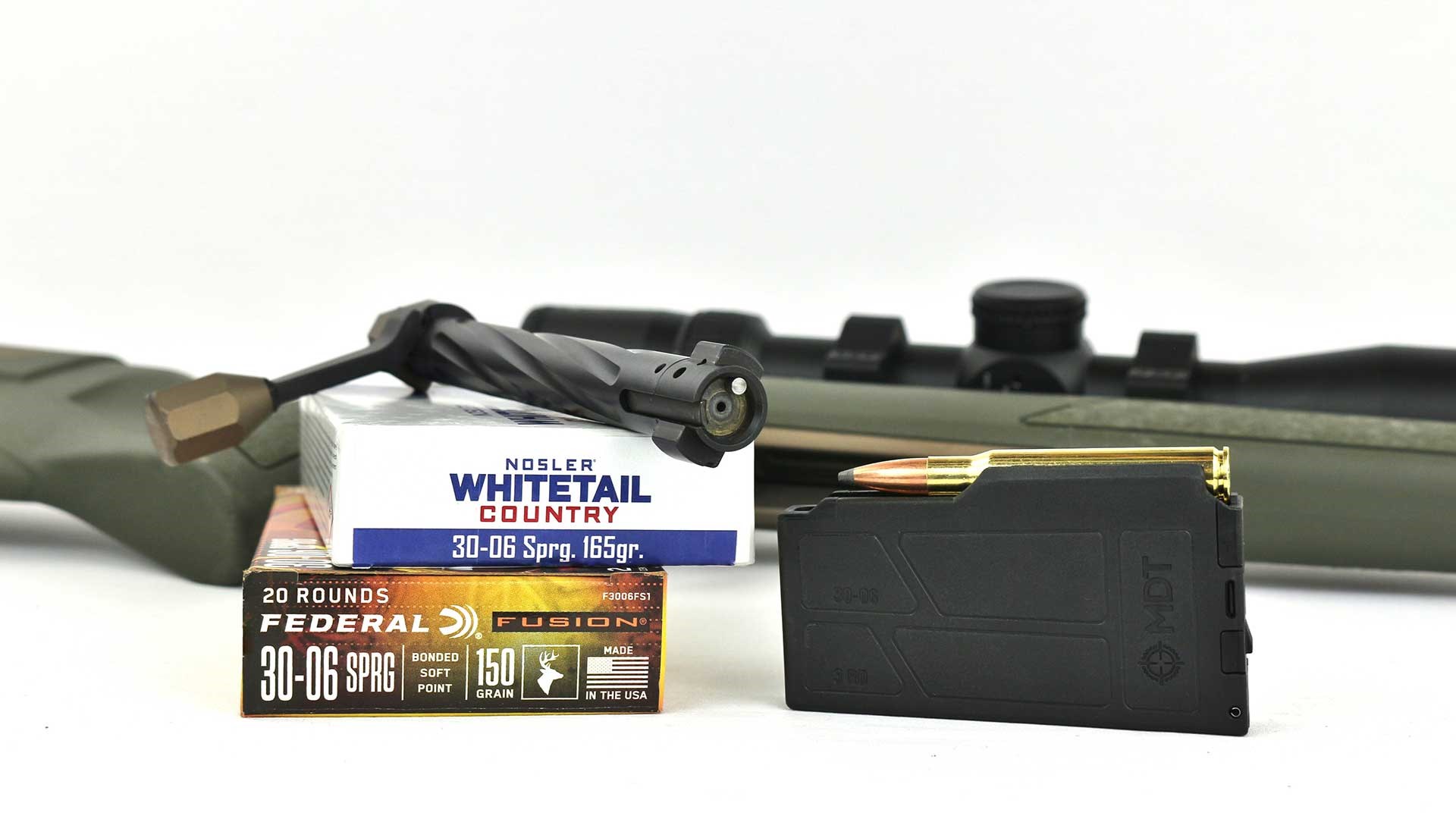 Bolt and detachable box magazine of the Christensen Arms Evoke bolt-action rifle next to two boxes of ammunition.