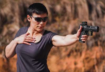 Tatiana Whitlock woman with gun shooting one-handed outdoors