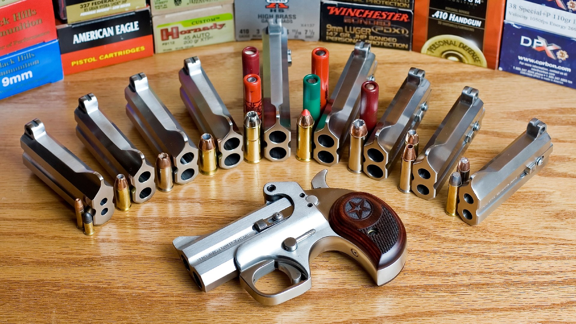 Bond Arms derringer barrels arrayed on a wood table, surrounding a Bond Arms pistol.