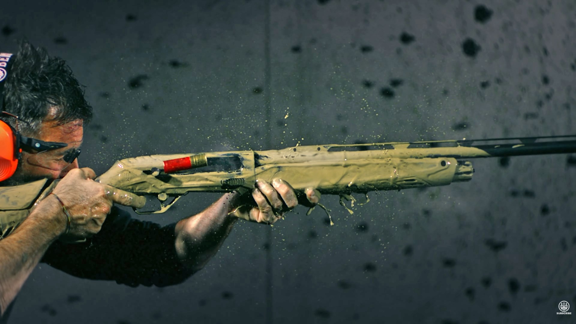 Man aiming and firing a mud-covered Beretta AX800 Suprema shotgun.