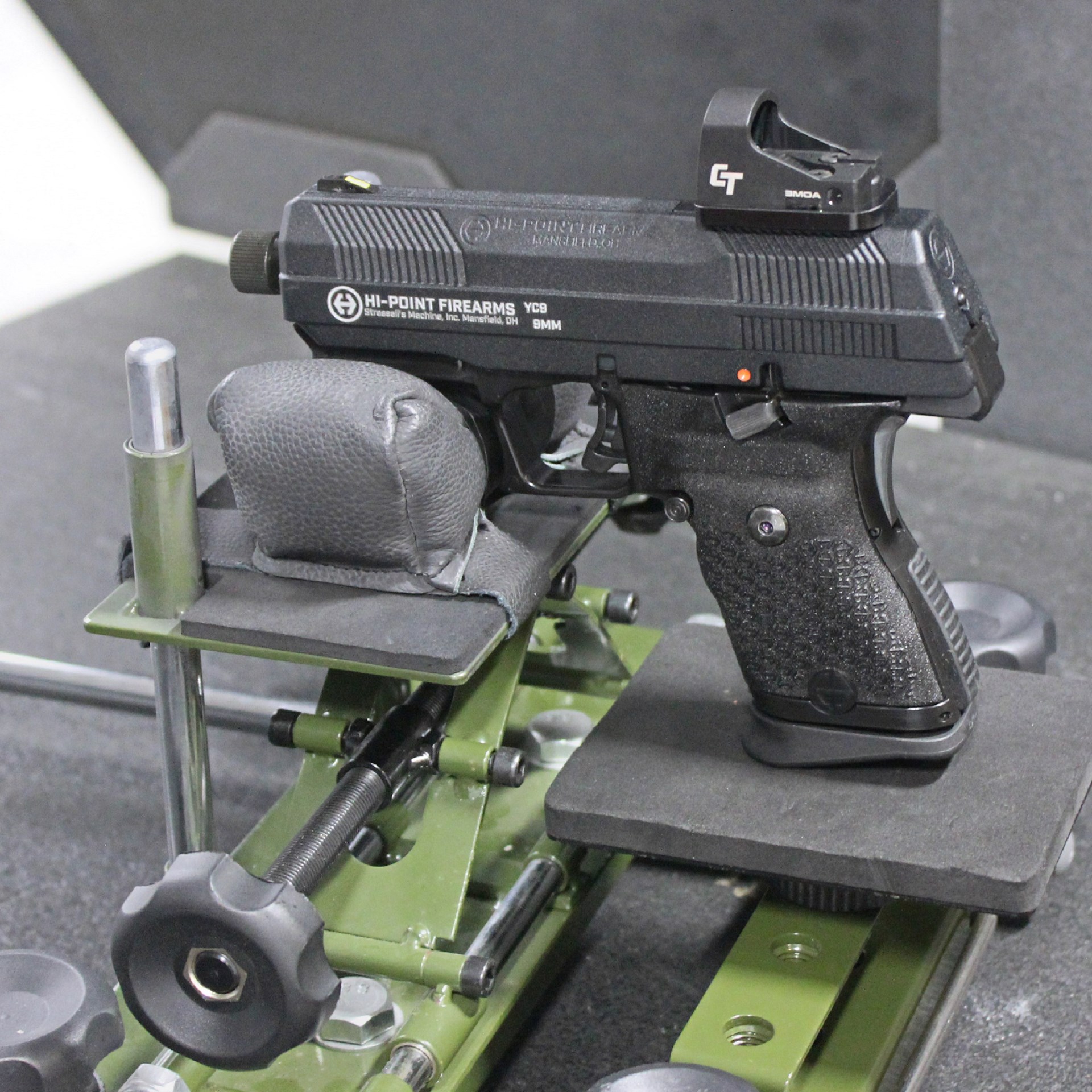 Hi-Point Firearms YC9RD handgun left-side view shown in gun rest at shooting range with Crimson Trace red-dot handgun optic mounted