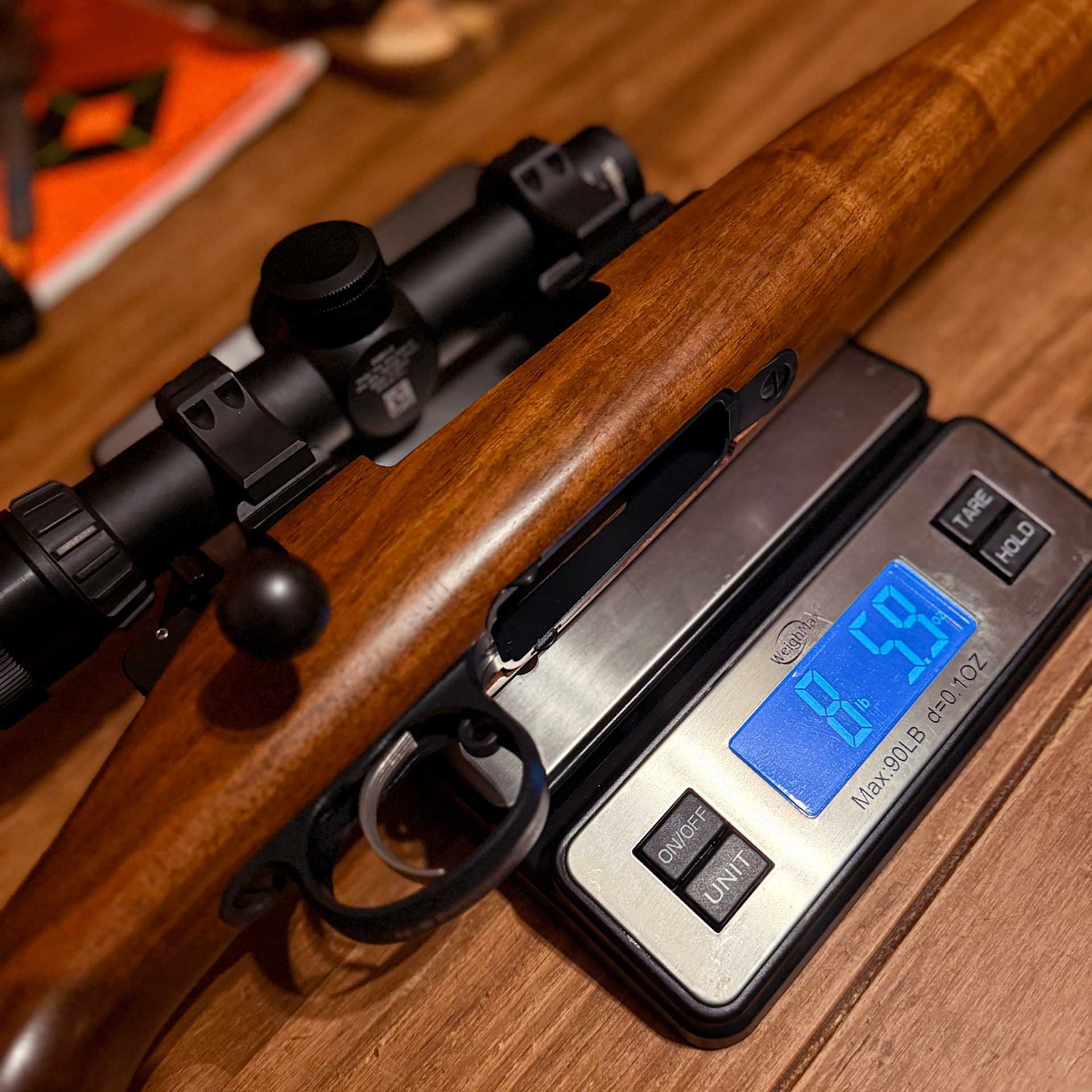 Wood-stocked rifle resting on a kitchen scale.