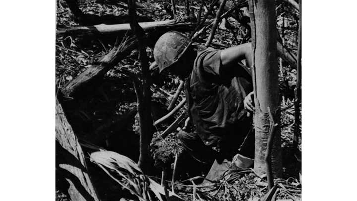 A Marine examining the entrance to an enemy tunnel complex during the summer of 1968.