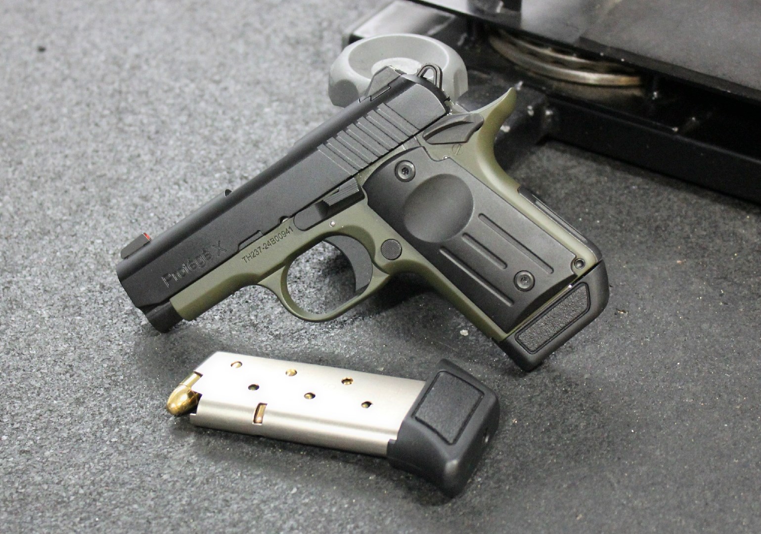 TriStar Arms Protege X propped up next to a loaded magazine on an indoor range.