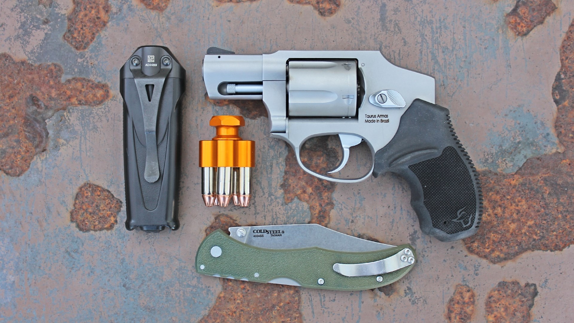 The Taurus 605 revolver next to a flashlight, knife and a five-round speedloader.