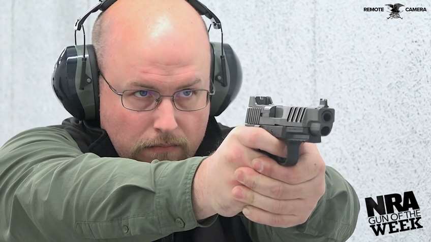 Man green shirt protective gear shooting pistol.