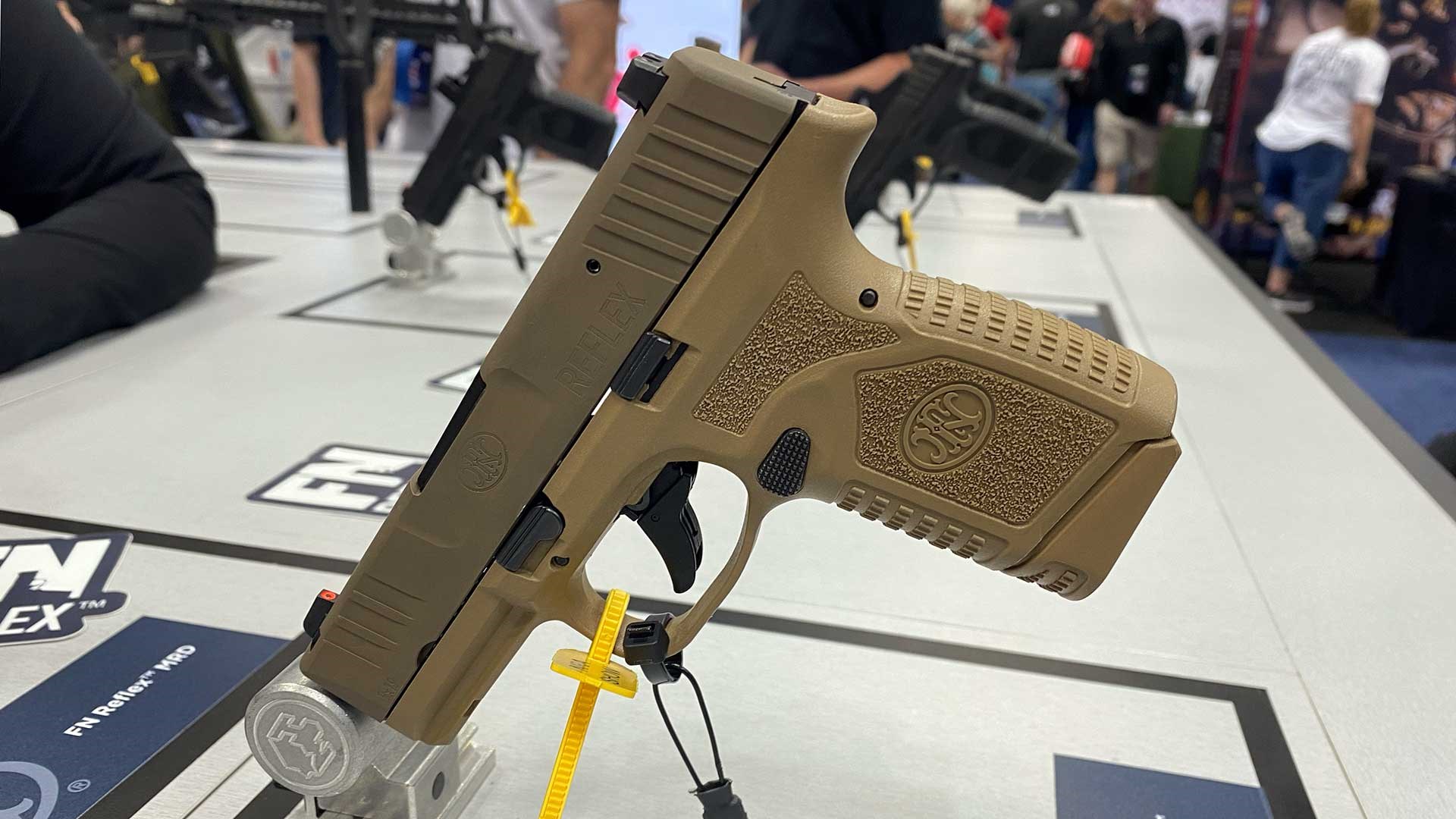 A tan FN America Reflex pistol shown on a display at the 2023 NRA Annual Meeting & Exhibits