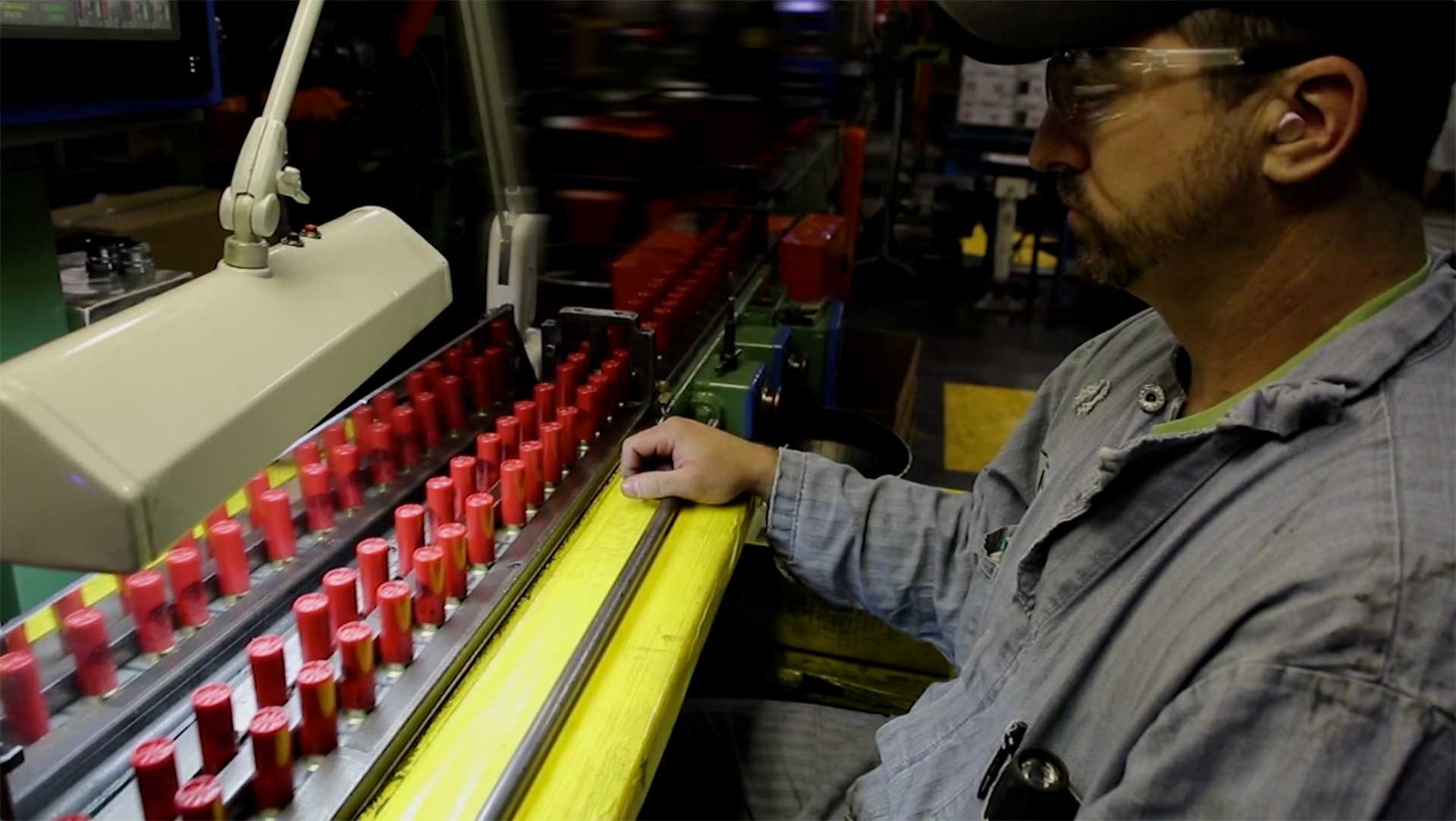 A man watches red Winchester shotshells being readied for packaging.