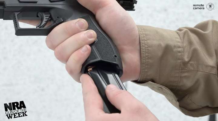 Masada pistol in shooter&#x27;s hand while being loaded with a magazine.