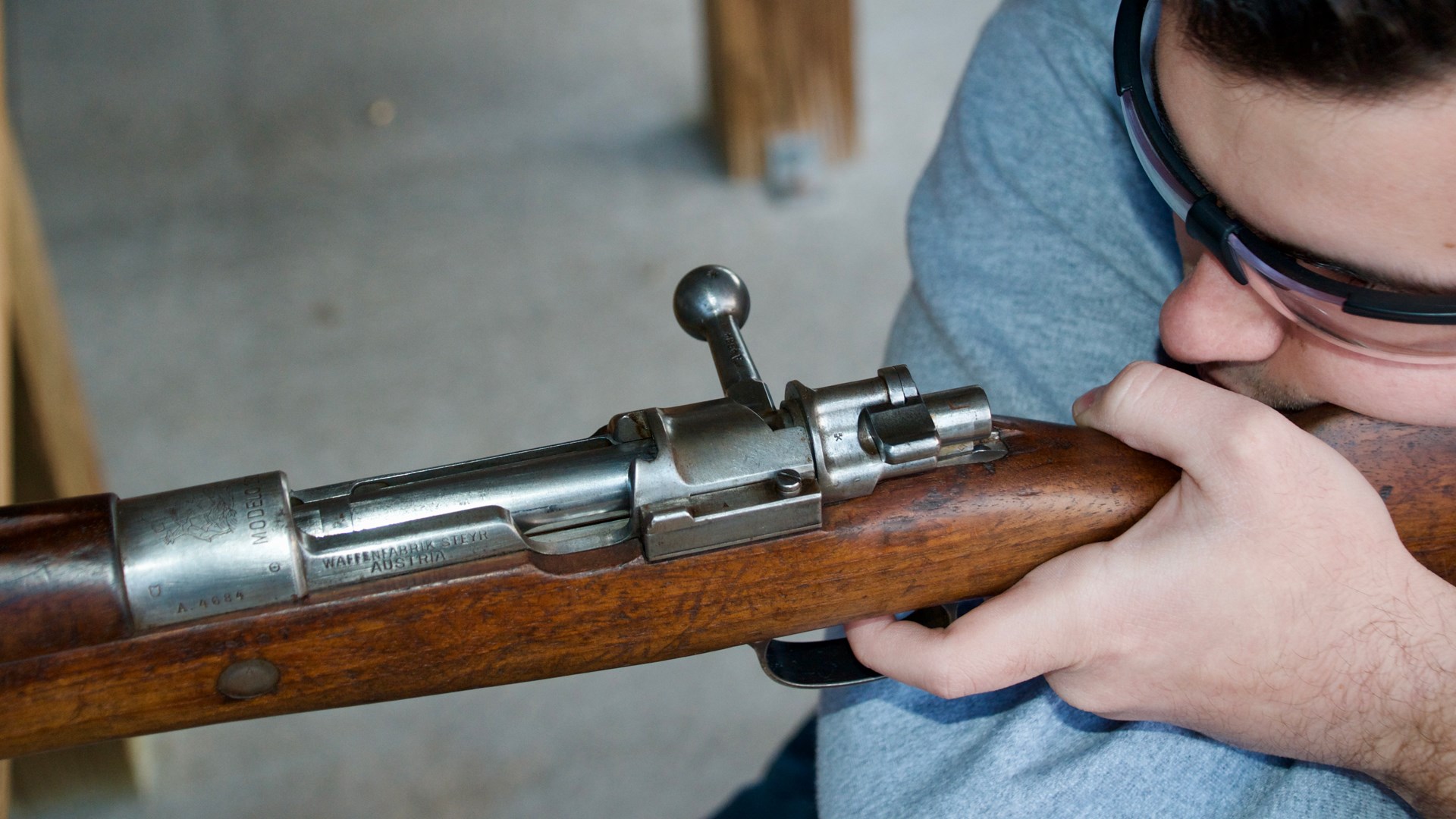 up-close view of bolt-action chilean mauser rifle being shot by man wearing glasses dark hair left-handed
