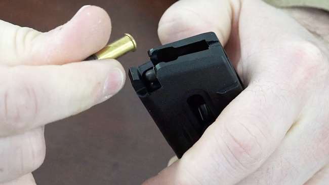 Glock G44 magazine in hands being loaded with .22 Long Rifle ammunition.