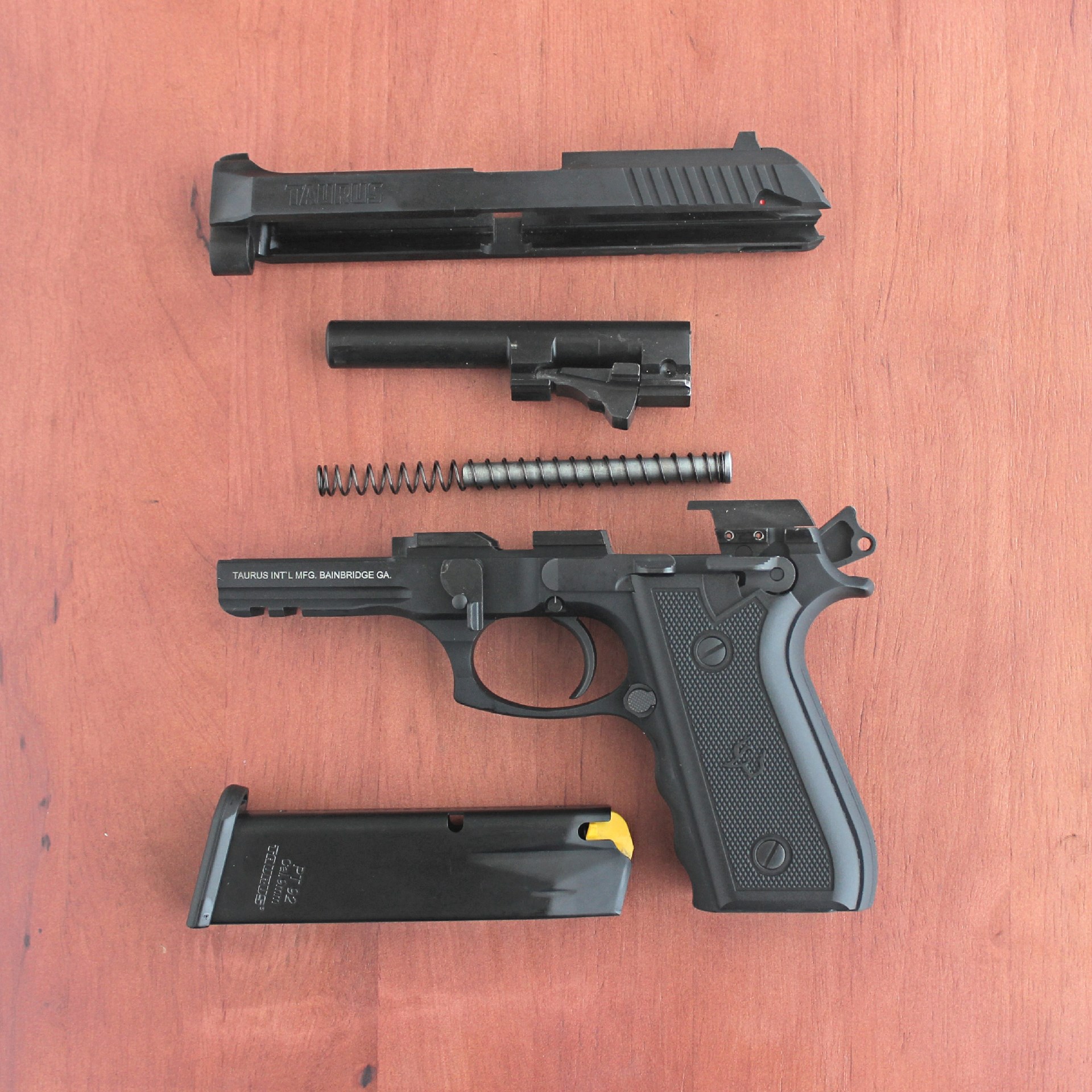 Taurus 917c pistol 9 mm disassembled view parts slide barrel spring frame magazine shown on wood