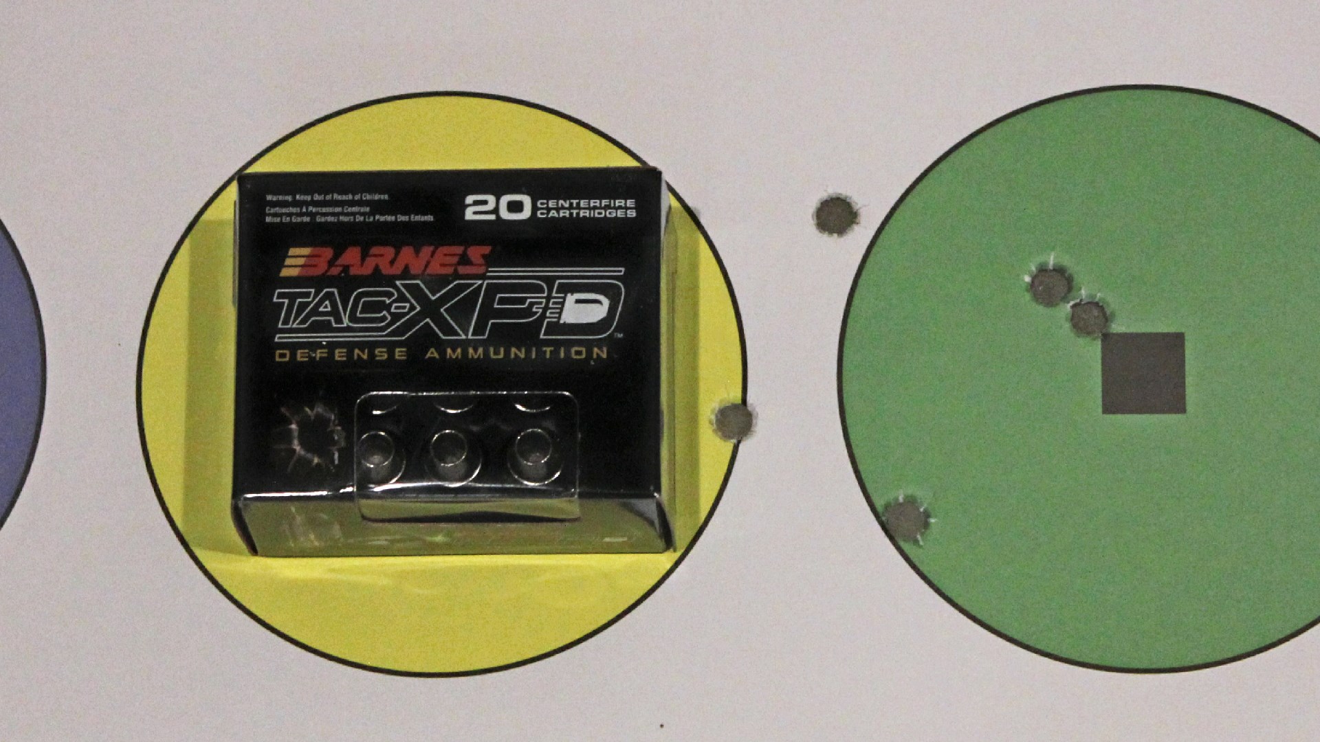 Shooting target shown with bullet holes next to ammunition box BARNES TAC-XPD