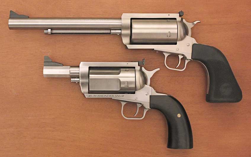 two stainless steel revolvers comparison guns big small large little wood background
