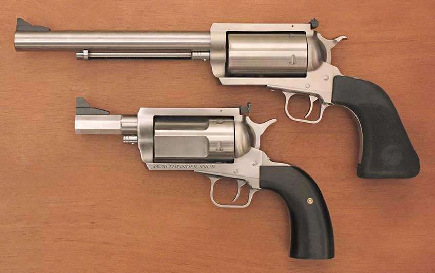 two stainless steel revolvers comparison guns big small large little wood background