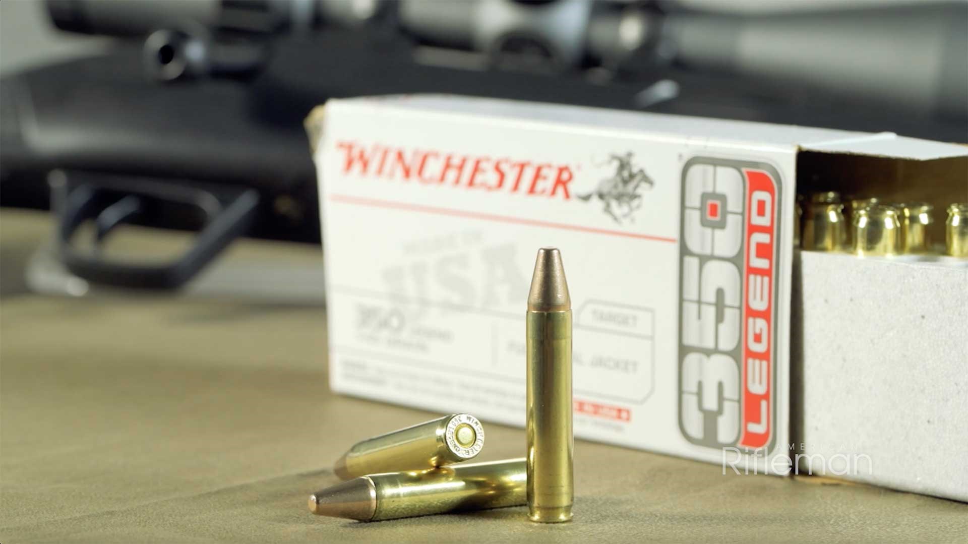 Several cartridges of Winchester's 350 Legend ammunition sitting on a table in front of an open, white box.