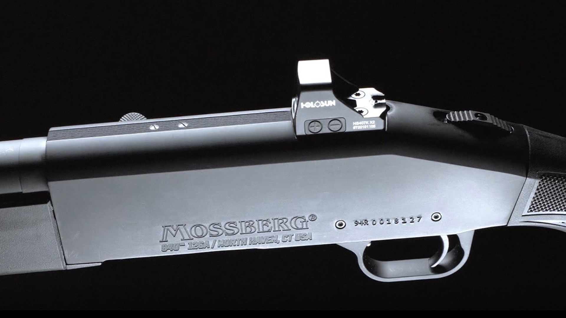 Holosun red-dot sight shown on top of a Mossberg shotgun receiver.