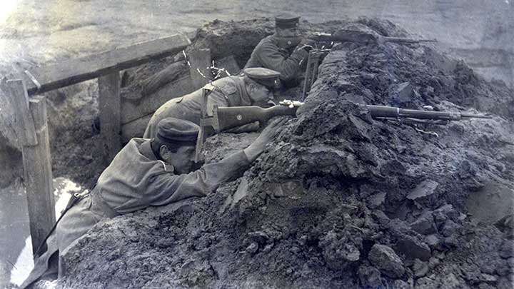 A German soldier takes a look through a pericope across no-man&#x27;s-land  while a comrade takes aim with a Gew 98.
