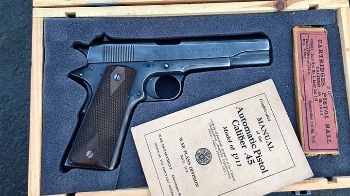 Another view of Capt. McKee&#x27;s Colt Model 1911 service pistol in a box along with period field manual and box of Frankford Arsenal .45 ACP ammunition.