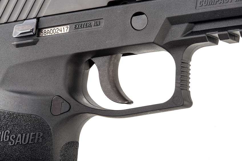 The curved trigger and undercut trigger guard of the SIG Sauer P320 show on white.