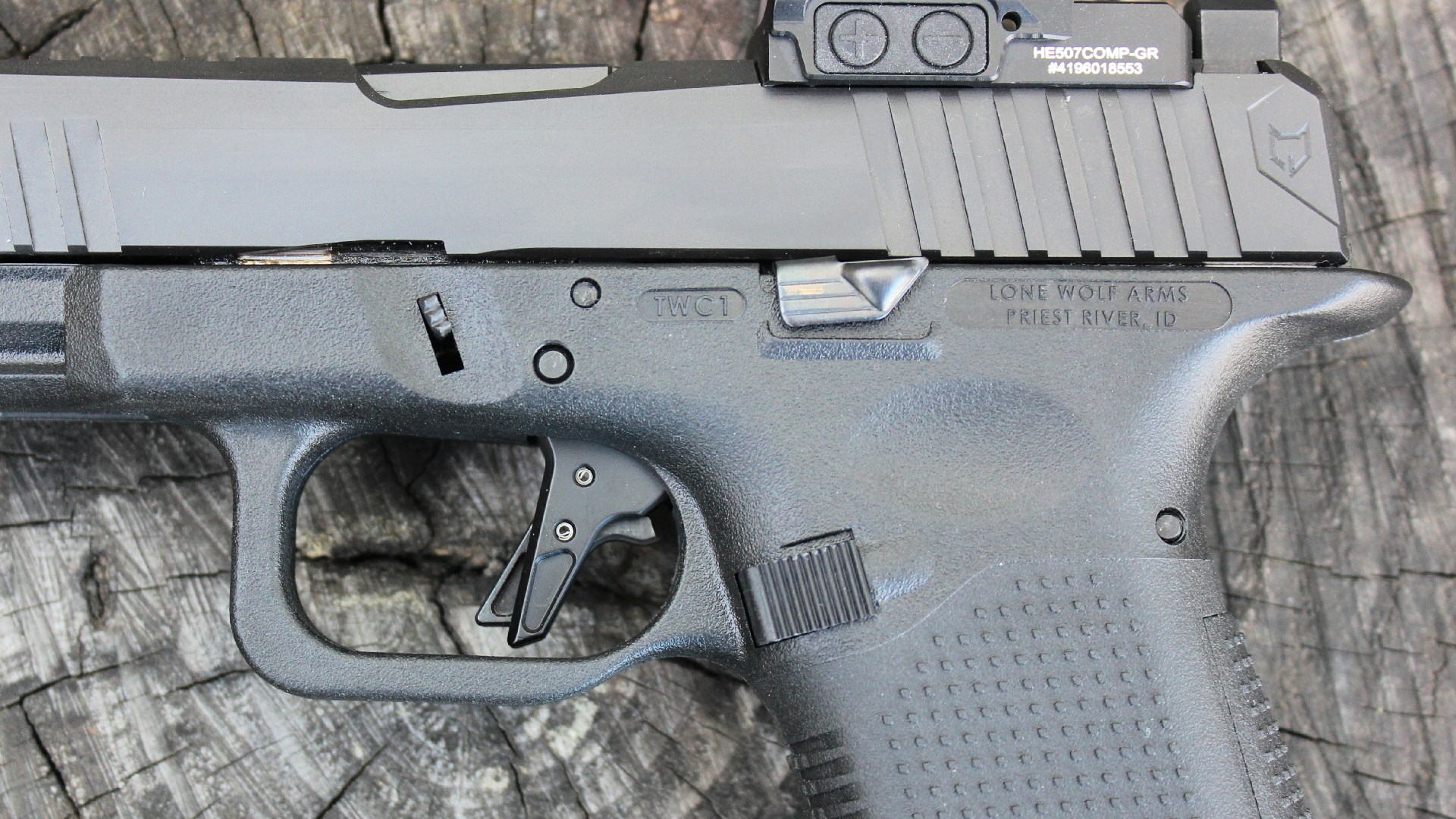 Left-side view of Lone Wolf Timberwolf 19X pistol close-up of controls black gun parts wood background