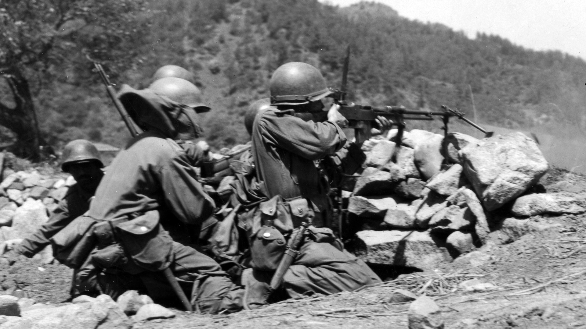 U.S. soldiers in Korea firing BAR with bipod and all attachments behind rocks trees hill background