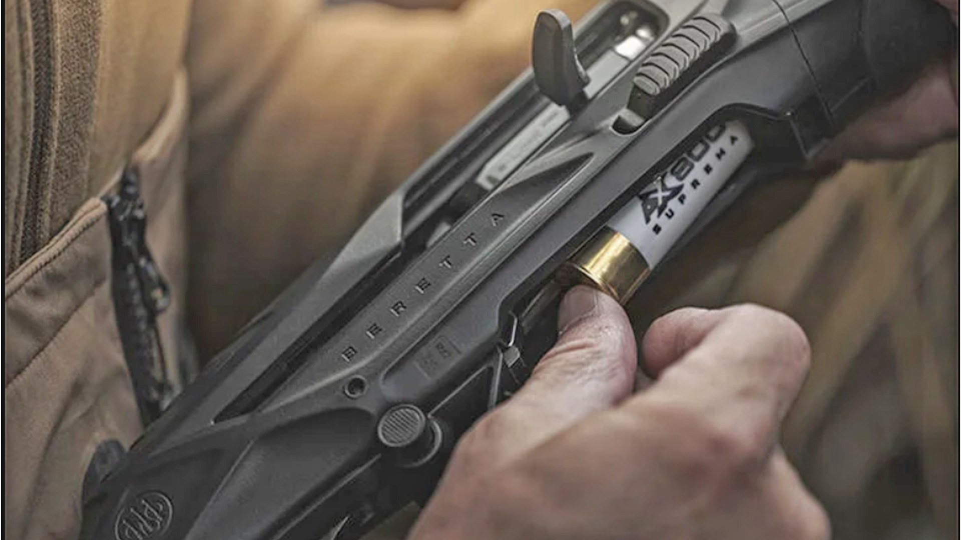 Hunter inserting a white shotshell into the tube magazine of the Beretta AX800 Suprema shotgun.