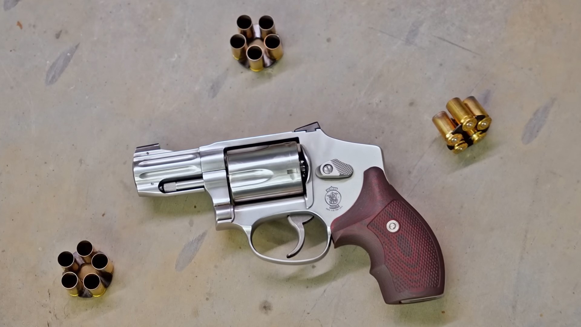 Left side of the Smith & Wesson 940 revolver, lying on a concrete floor, surrounded by brass cases in moon clips.