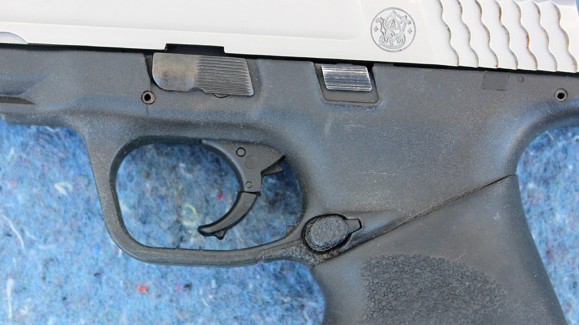 Left-side close-up view of Smith & Wesson M&P 40 pistol contols frame trigger slide stop magazine release takedown lever slide serrations stainless steel top